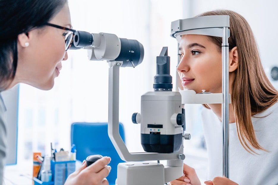 photo of eye doctor giving young woman an eye exam